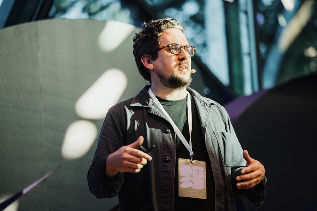 Ben Keenan presenting on stage during a session at DO23: Rediscover Creativity.